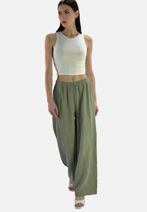 Pantaloni a gamba larga verde chiaro, con finitura testurizzata e vita elastica, abbinati a un top aderente bianco e sandali bianchi con tacco.