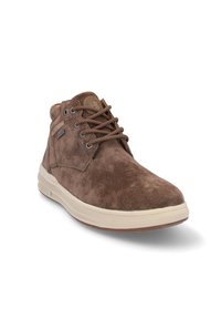 Botas de ante marrón hasta el tobillo con puntera redonda, parte superior texturizada, suela crema y cordones marrones. Presenta un logotipo circular en el lado exterior.