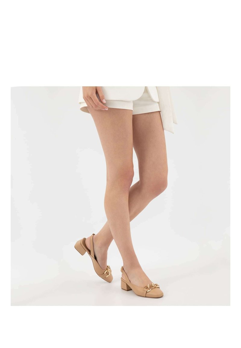 Décolleté beige con punta quadrata, tacco a blocco basso e un accento decorativo a forma di fiocco sul davanti. Texture in pelle liscia.