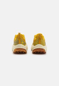Scarpe sportive gialle e grigie con tomaia in rete testurizzata e suola ammortizzata. Presentano un retro rinforzato con il logo Vibram.