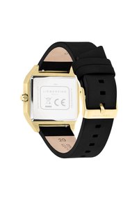 Montre connectée carrée avec boîtier en acier inoxydable doré, bracelet en silicone noir et dessous en cuir beige. Présente un cadran argenté minimaliste.