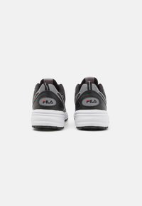 Scarpe da ginnastica nere e grigie con tomaia texturizzata, suola bianca prominente e logo FILA rosso sul tallone. Accenti riflettenti sui lati.