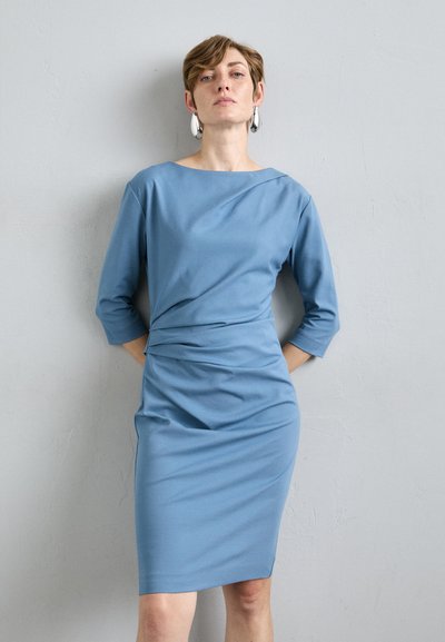 Vestido azul ajustado en un tejido suave con mangas tres cuartos, detalles drapeados en la cintura y un dobladillo a la altura de la rodilla.