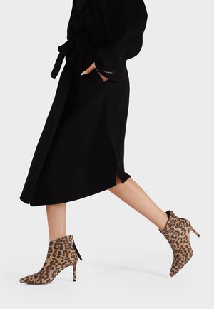 Stivaletti alla caviglia con stampa leopardata, punta affilata, tacco a stiletto e chiusura con zip. Realizzati in materiale morbido, presentano una silhouette elegante.