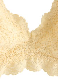 Beige blonder med indviklede blomster- og prikkede mønstre, bølgede kanter og en gennemsigtig, delikat tekstur.