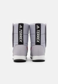 Grå polstrede støvler med sort og hvid branding, der har en robust sål og teksturerede bagpaneler for støtte og holdbarhed.