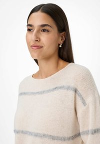 Lichtbeige trui met een losse pasvorm, voorzien van grijze horizontale strepen. Zachte, gebreide textuur, ronde halslijn en wijde mouwen.