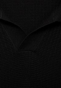 Maglione nero lavorato a maglia con scollo a V, caratterizzato da un tessuto testurizzato e dettagli con colletto a costine. Il materiale sembra morbido ed elastico.