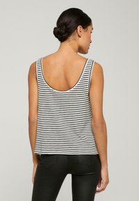Top a righe bianche e nere con schiena a cucchiaio, realizzato in tessuto morbido. Il design presenta spalline larghe e una vestibilità ampia per il massimo comfort.