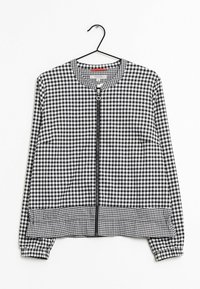 Chaqueta de cuadros en blanco y negro con mangas largas, cuello redondo, cremallera frontal y puños y dobladillo elásticos. Cuelga de un gancho negro.