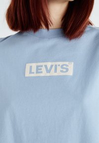 Lyseblå bomulds t-shirt med et rektangulært hvidt Levi's-logo på forsiden. Designet har rund halsudskæring og korte ærmer.