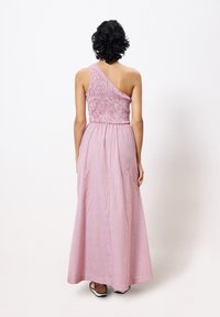 Robe asym�étrique à une épaule en rose avec un corsage texturé et une jupe fluide. Longue avec une taille cintrée, motifs minimalistes et couleur unie.