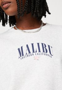 Šedá bavlněná mikina s nápisem "MALIBU SOUTHERN CALIFORNIA" v tmavě modré barvě, na přední straně s květinovými akcenty v růžové a zelené barvě.