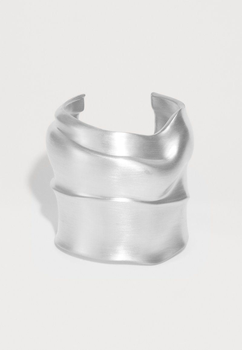 Φαρδύ ασημένιο βραχιόλι με μαλακή, κυματιστή και ελαφρώς κυματιστή υφή σε λευκό φόντο.