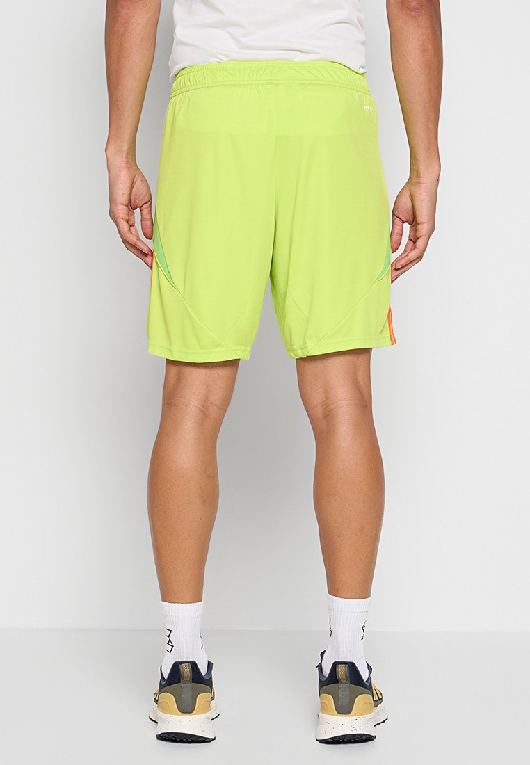 Shorts de sport vert fluo avec une taille élastique, texture lisse et poches latérales. Présente des accents de couleur contrastante sur les côtés.