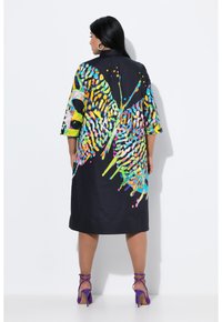Bunt gemustertes Kleid mit schwarzem Grund, das auffällige abstrakte Designs in leuchtenden Farben zeigt. Kurze Ärmel und lockere Passform.