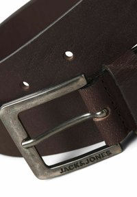 Ceinture en cuir marron avec une surface texturée, boucle en métal argenté avec une marque gravée, et plusieurs trous d'ajustement.