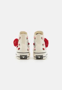 Høye kanvas sneakers i off-white med broderte røde og rosa roser, svarte gummisåler og et karakteristisk Converse-logo merke.