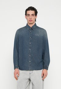 Πουκάμισο από τζην ύφασμα, σκούρο μπλε, με μακριά μανίκια, κουμπιά μπροστά, κεντητό λογότυπο "Diesel", κανονικό γιακά, εφαρμοστή σχεδίαση, με ανοιχτόχρωμη φθορά στους ώμους.