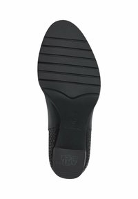 Semelle de chaussure en caoutchouc noir présentant des rainures horizontales pour l'adhérence, un marquage en relief de la marque, et un design texturé près du talon.