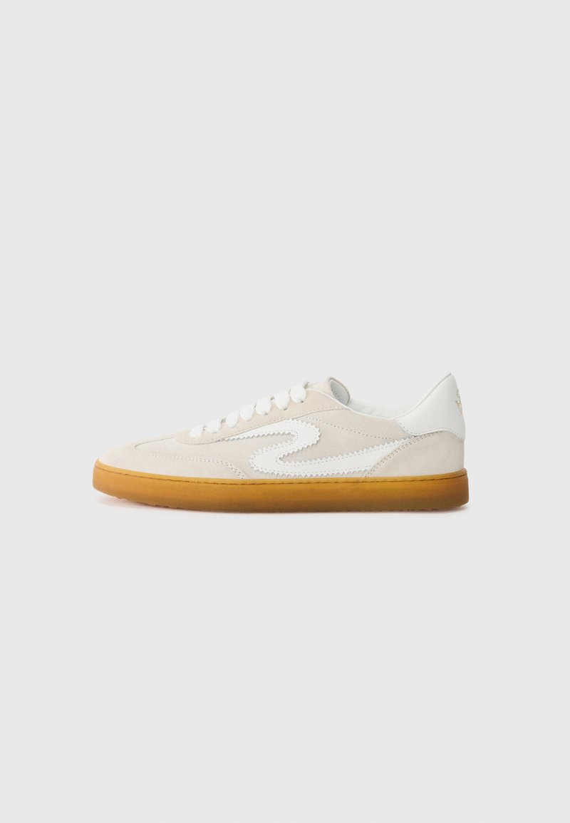 Baskets en daim beige avec des accents en cuir blanc, semelle en caoutchouc naturel et bout rond. Présente un design distinct en forme de virgule sur le côté.