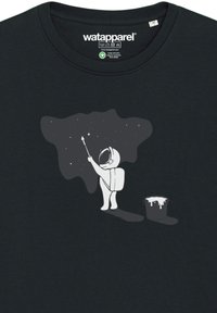 Donker T-shirt met een afbeelding van een astronaut die sterren op een donkere wolk schildert, naast een verfbakje met witte verfdruppels.