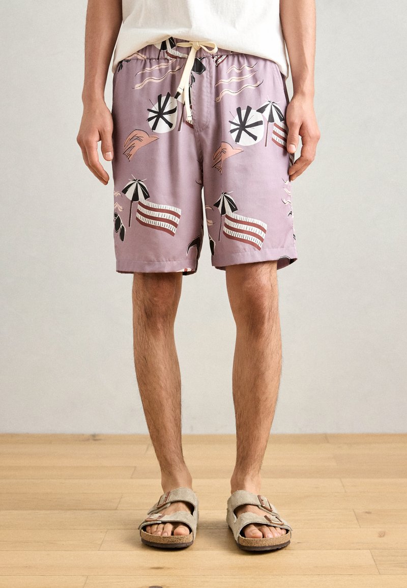 Shorts de bain lilas avec des imprimés sur le thème de la plage comme des parapluies et des vagues, dotés d'une taille élastique et d'un cordon de serrage.