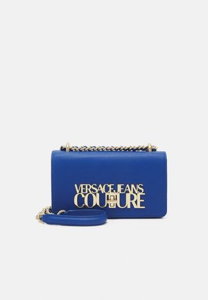 Blauwe leren handtas met goudkleurige kettingband en groot goudkleurig "Versace Jeans Couture" logo op de voorsluiting.