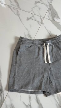 Gray shorts made of soft fabric, featuring an elastic waistband with white drawstrings and side pockets. Standard loose fit design.