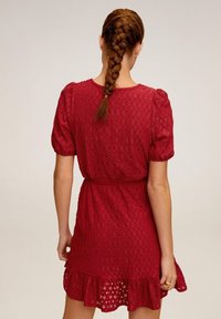 Rotes kurzes Kleid mit Puffärmeln, Spitzenmuster und Rüschensaum. Verfügt über eine taillierte Taille und ein Rückband-Detail.