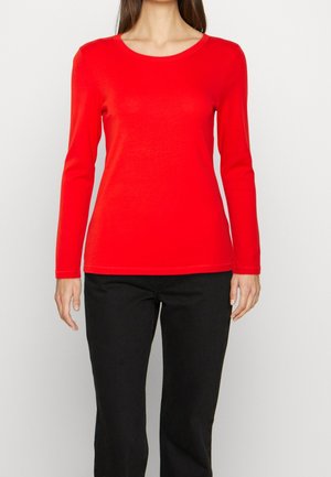 Czerwona koszula z długim rękawem wykonana z rozciągliwej tkaniny, z okrągłym dekoltem i dopasowanym krojem, w zestawieniu z czarnymi spodniami.