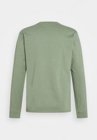 Langarmhemd in einem gedämpften Grünton, aus weicher Baumwolle, mit Rundhalsausschnitt und Nahtdetails an den Schultern und Bündchen.