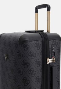 Valigia rigida nera con superficie testurizzata, accessori in oro, doppi zip, manico telescopico e emblema del logo sul fronte.
