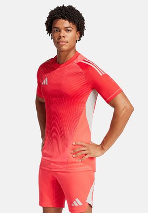 Rode sportshirt met een textuurverlooppatroon, aangevuld met bijpassende shorts. Bevat het Adidas-logo en gestreepte accenten op de mouwen.