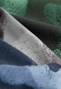 Des textiles de couleurs variées : bleu foncé, gris et noir avec des motifs abstraits et des éclats. Tissu doux avec une surface légèrement texturée.