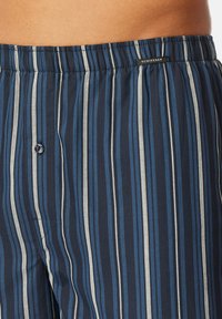 Blauwe en marineblauwe gestreepte herenpyjamashorts met een elastische tailleband, een knoopsluiting en een klein label op de tailleband.