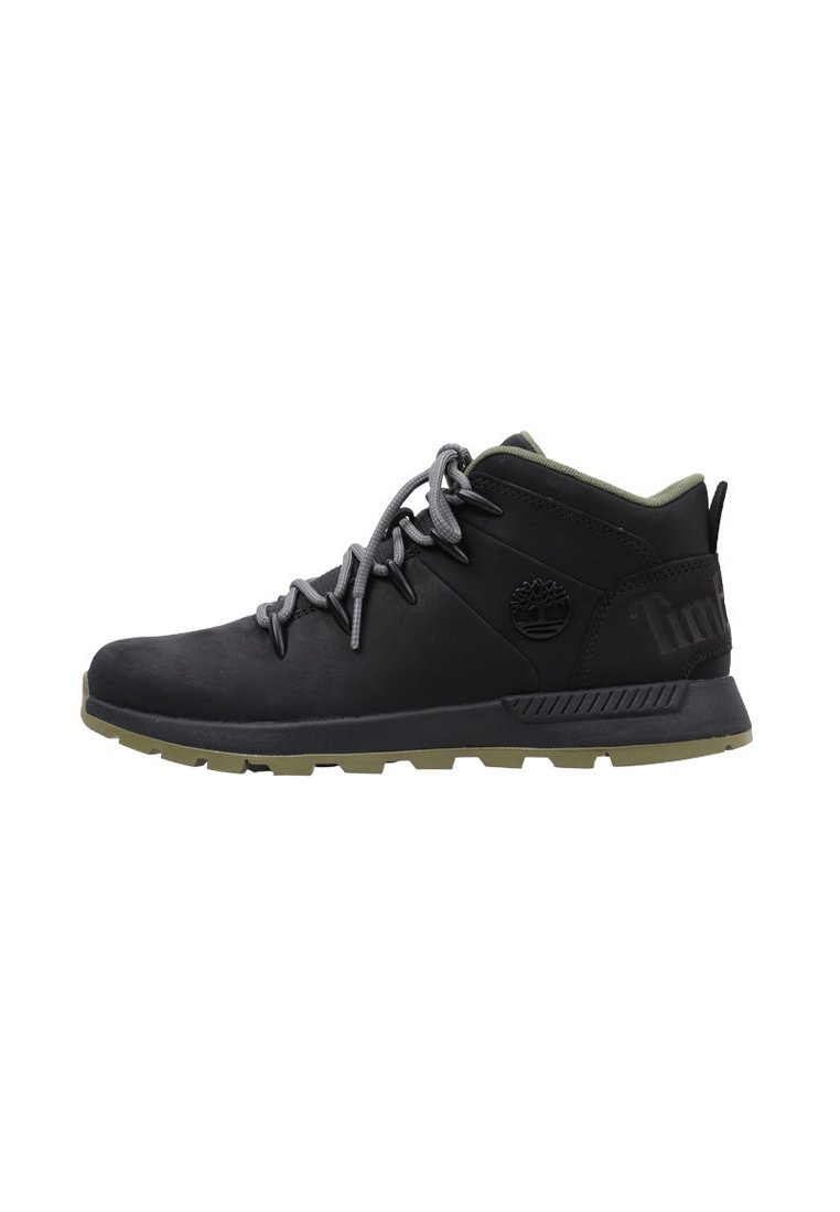 Zapatillas de senderismo de media altura negras con cordones grises, suela de goma y un cuello acolchado verde; presenta un logo en el lateral y detalles texturizados.