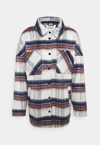 Geruite flanellen shirt in wit, marineblauw en koraal, met een knoopsluiting aan de voorkant, lange mouwen en twee borstzakken met contrasterende patronen.