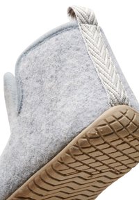 Grå kännslig toffel med en texturerad yta, med gummisula och vävd hälaccent. Rundad form och mjukt material för komfort.