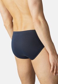 Tummansininen puuvillainen miesten alushousut, joissa on sileä pinta, joustava vyötärönauha ja minimalistinen muotoilu, jotka näyttävät tiukalta takaviistosta.