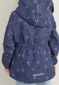 Veste bleu marine à fleurs avec capuche, taille élastiquée, et "NORTHVILLE" imprimé dans le dos. Fabriquée en tissu texturé avec de petits imprimés colorés.