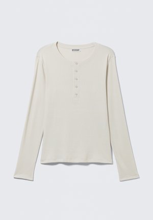 Langärmeliges cremefarbenes Henley-Shirt mit rundem Ausschnitt und Fünf-Knopf-Leiste, mit dem Label Weekday, auf einem neutralen Hintergrund flach ausgelegt.