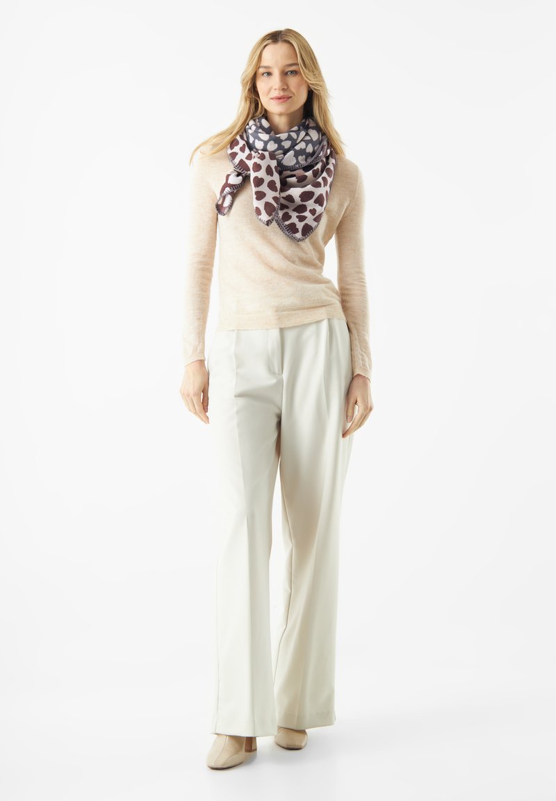 Helle beige Strickjacke, cremefarbene weit geschnittene Hose und ein gemusterter Schal in Grautönen und Burgunderrot mit Herzmotiven, locker um den Hals gebunden.
