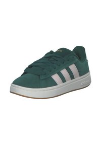 Gröna mockaskor med vit tre-stripes design, snörning framtill, vadderad tunga och gummisula. Guldlogotyp detaljerad på tungan.