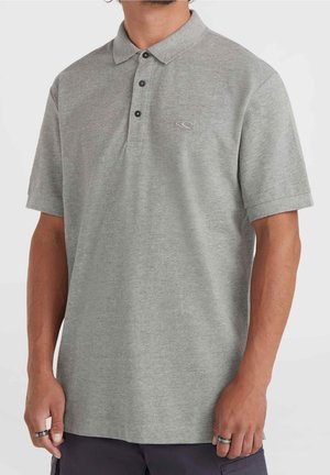 Hombre con camiseta tipo polo de manga corta gris con tres botones y pequeño logo bordado en el pecho, combinado con pantalones oscuros.