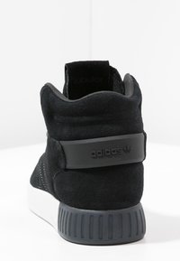 Baskets montantes en daim noir avec une semelle en caoutchouc, dotées d'un panneau arrière texturé, de détails brodés et d'un logo sur le côté.