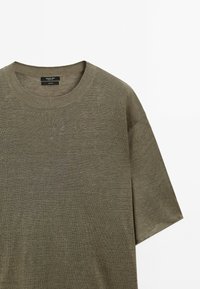 Oliivinvihreä lyhythihainen neulottu t-paita pyöreällä pääntiellä, jossa on sileä pinta ja hienovarainen resorikuviointi pääntien ympärillä.