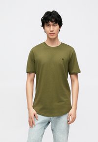 Kortärmad t-shirt i olivgrönt, tillverkad av mjukt tyg, med rund halsringning och en liten svart logotyp på vänster bröst.