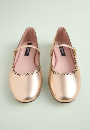 Ballerines Mary Jane métalliques dorées avec bord festonné, détails ajourés et petite bride à boucle. Texture cuir lisse, semelle intérieure rose.