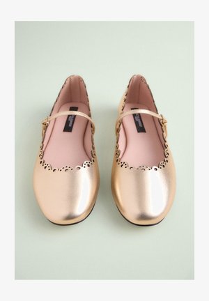 Goldene Mary Jane Ballerinas aus Metallic-Leder mit wellenförmigem Rand, Ausschnitten und einem kleinen Schnallenriemen. Glatte Lederstruktur, pinkfarbene Innensohle.